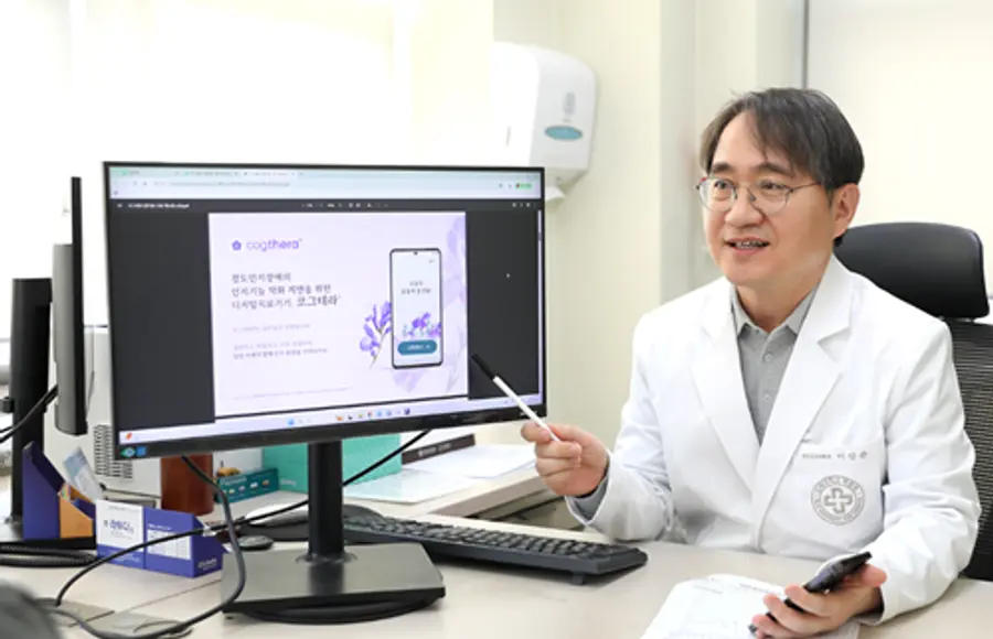사진 : 이강준 교수가 외래 진료실에서 환자에게 모바일 기반 인지중재 치료 프로그램 ‘코그테라’의 주요 기능과 기대 효과를 안내하고 있다.